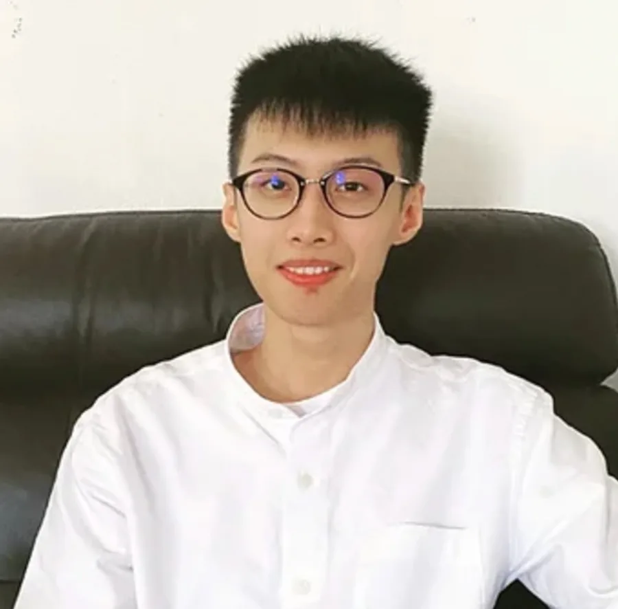 Smiling person in white shirt with glasses.