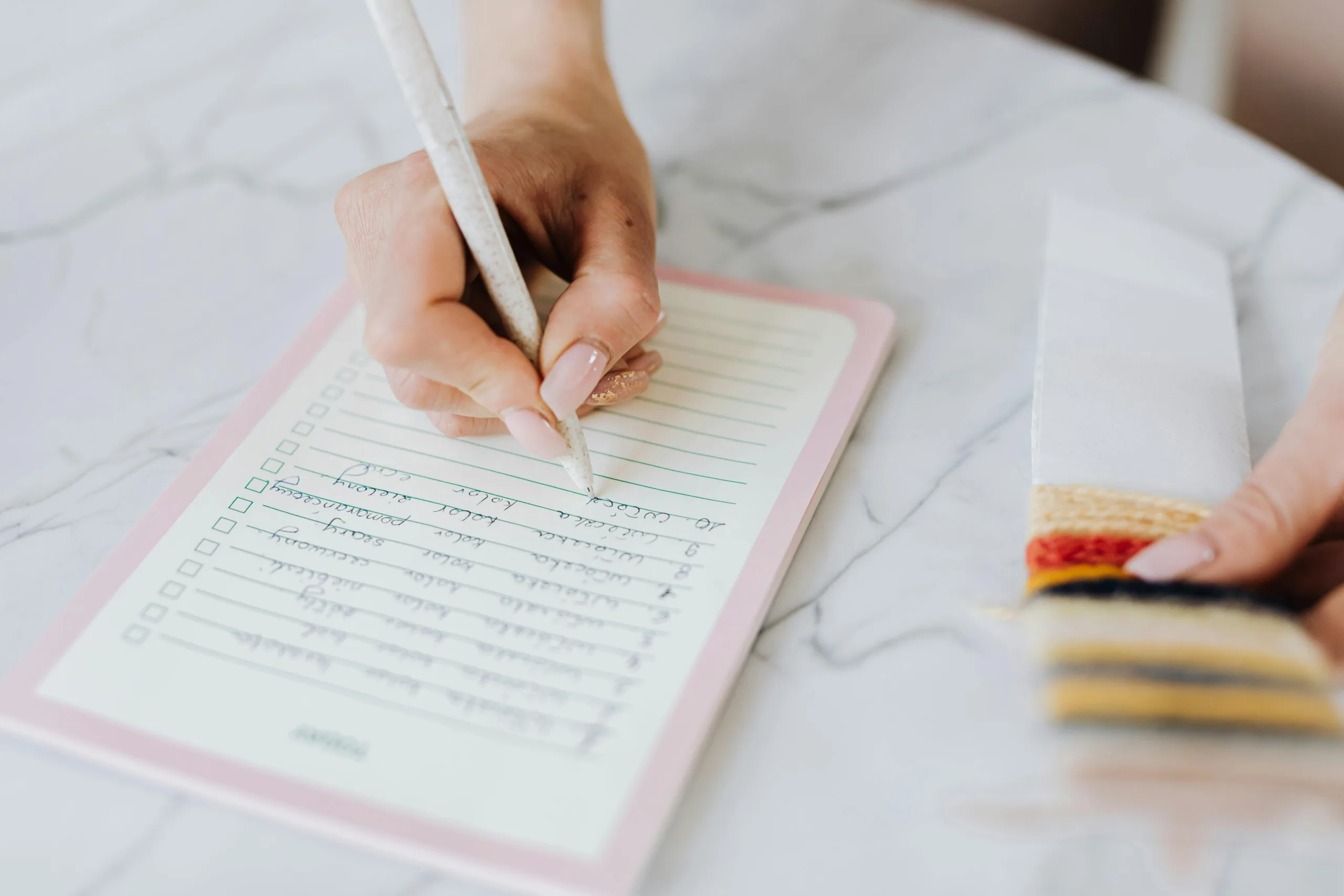 Person writing checklist on notepad