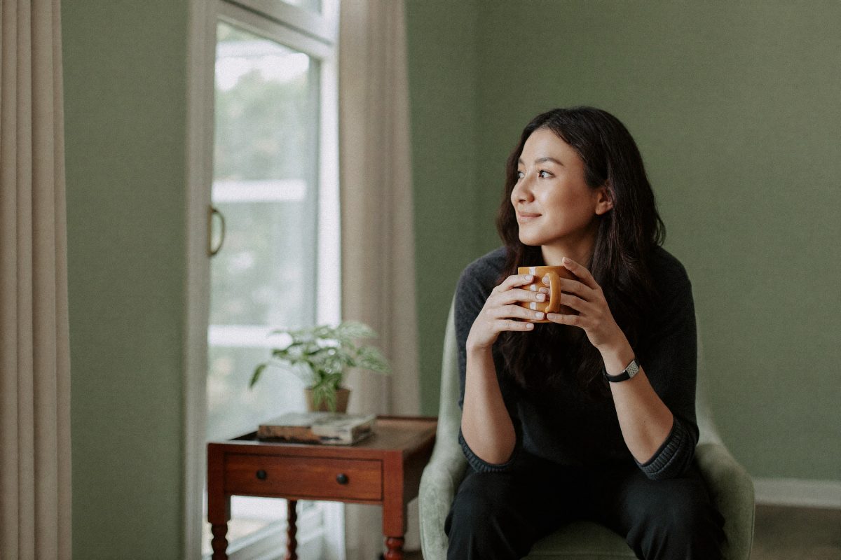 A woman sitting quietly with a warm drink in a calm counselling room