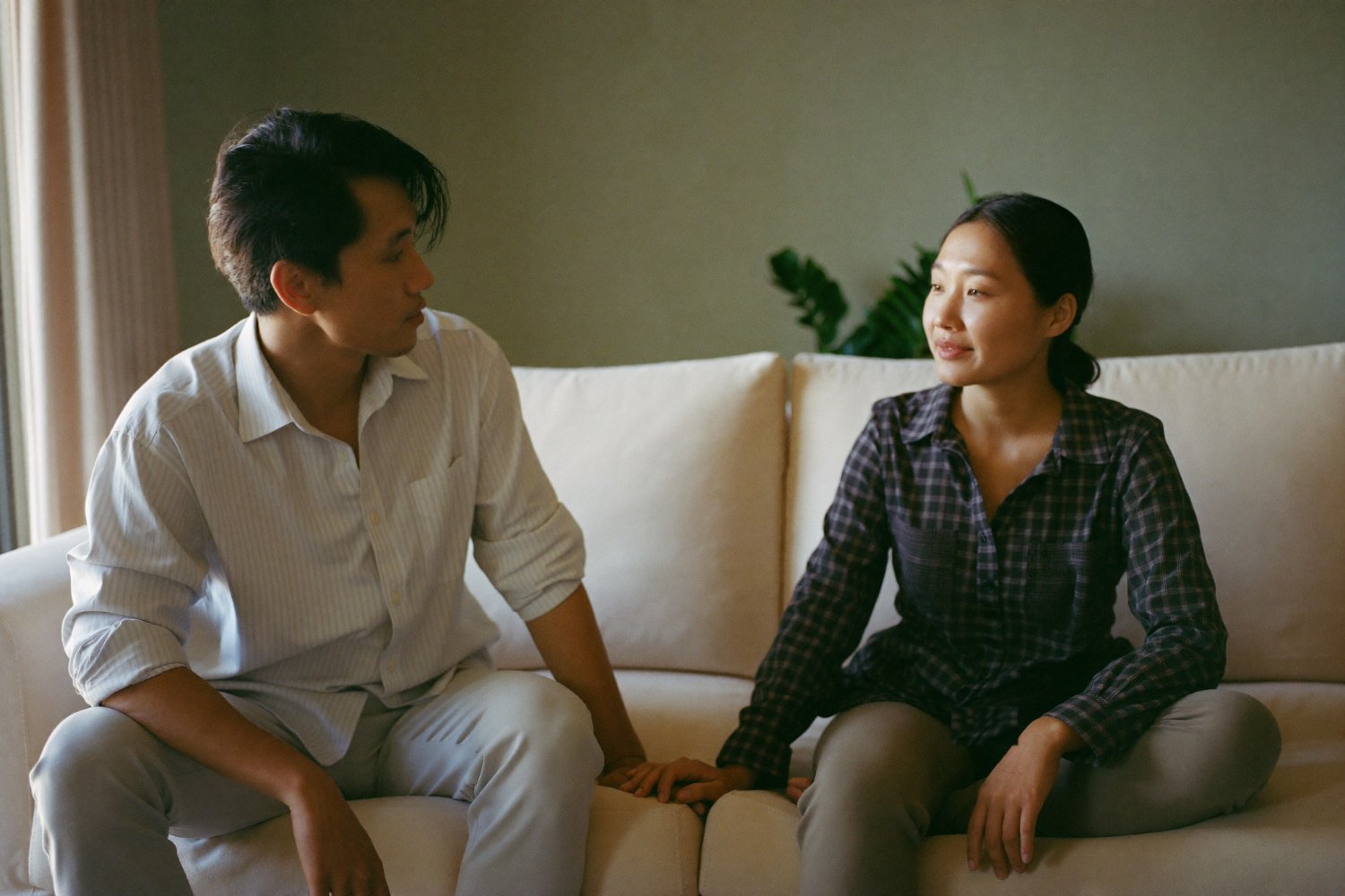 Couple sitting together on a sofa holding hands after a counselling session