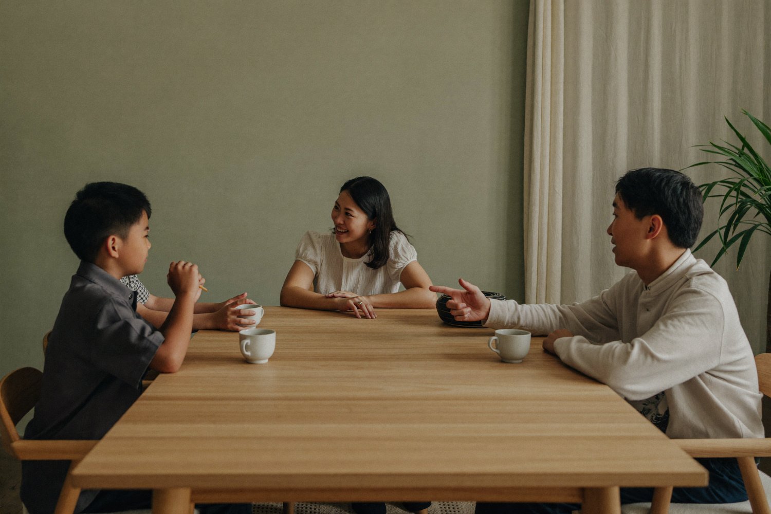 Malaysian family of four talking together around the dining table at home