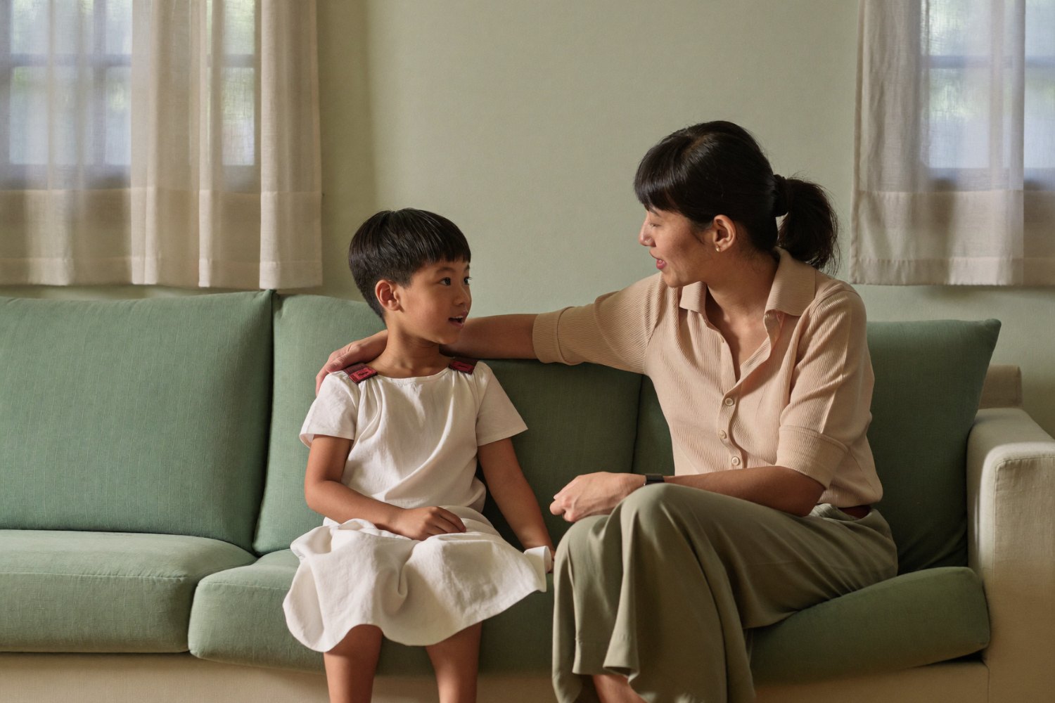 Mother and young child sitting together on a sofa, talking calmly — parent support at BeLive in Psychology