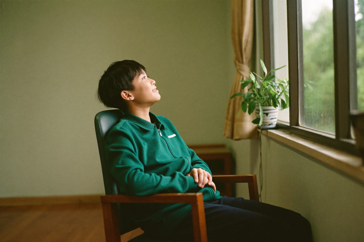 A teenager sitting calmly by a window during a counselling session