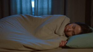 A person asleep on their side in the blue light before dawn