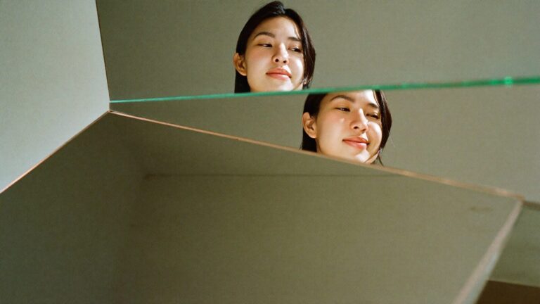 A woman's face reflected at different angles in a set of mirrors, each showing a different expression