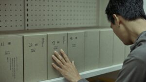 A hand hovering hesitantly beside boxes on a shop shelf