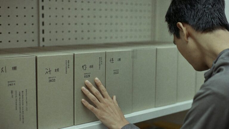 A hand hovering hesitantly beside boxes on a shop shelf