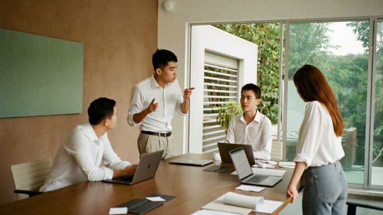 Three young professionals talking around a high table in a bright modern office