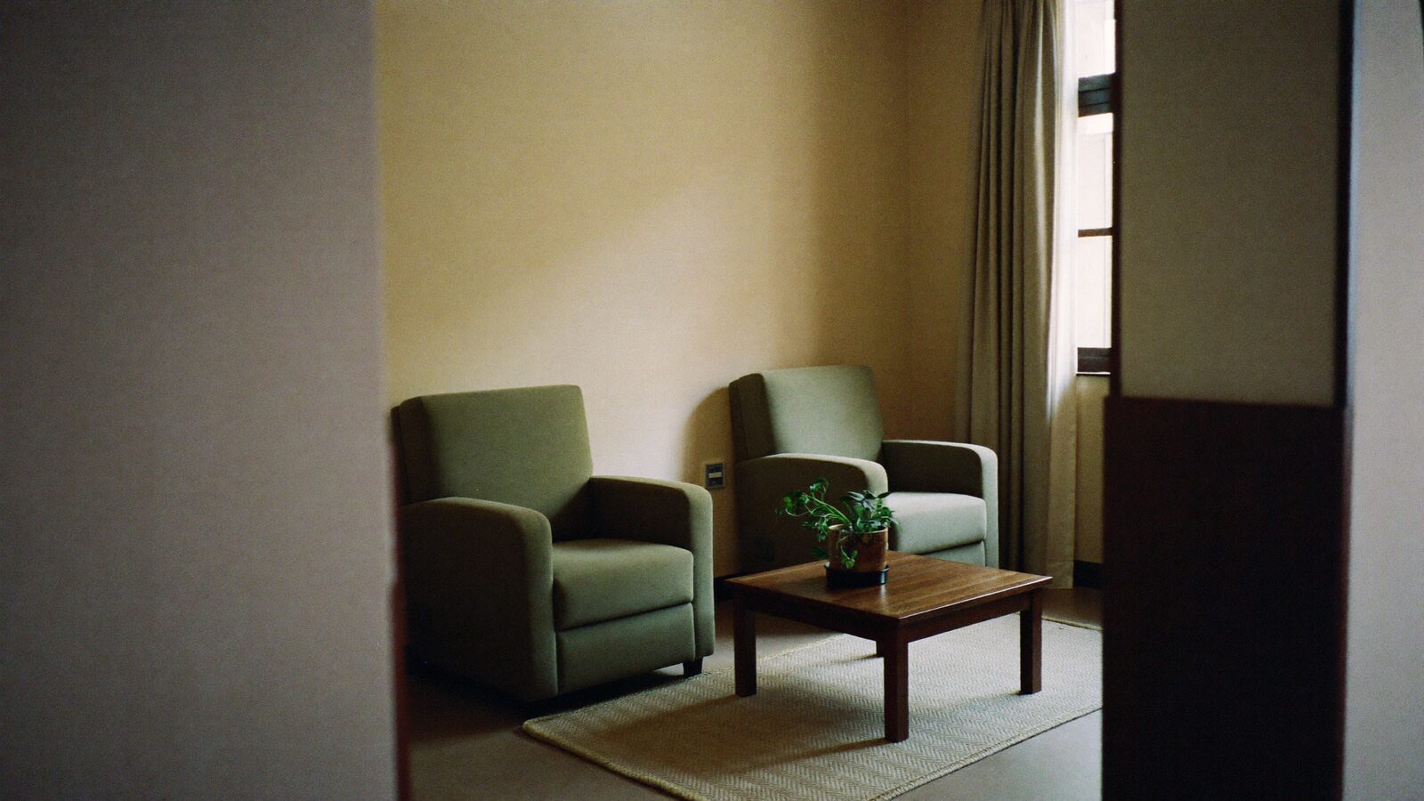 A welcoming counselling room with two armchairs facing each other and a tall window