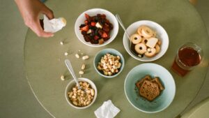Bowls of nuts, crackers and dried fruit spread across a coffee table with a hand reaching in