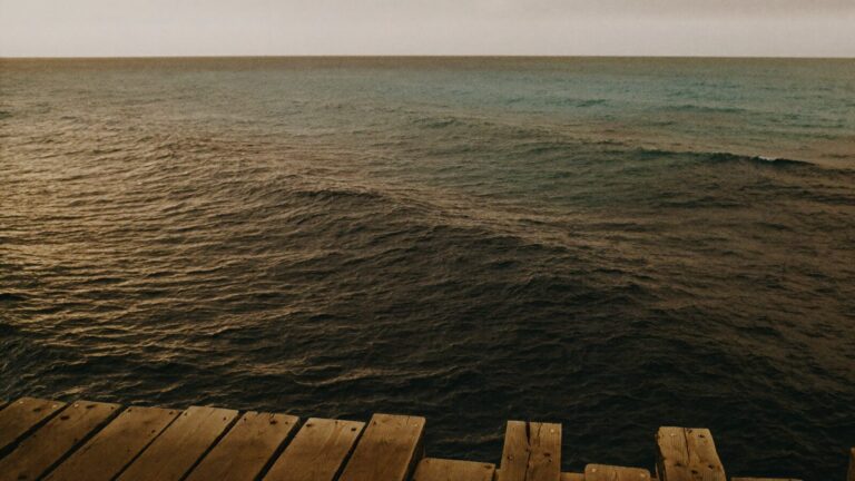 The dark open sea seen from the end of a weathered timber jetty
